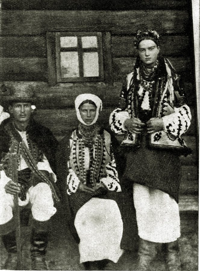 Покуття, пов. Вижниця. Жінки у вовняних полосатих запинках заткнених за пояс. Кожушки вишиті коліровою шкіркою та волічкою. Рукави богато вишивані. У жінки біла завійка на голові. Дівчина закосичена квітами, волічкою та мушлями. (Із видання "Österreich im Wort u. Bild" з Музею Н.Т.Ш. у Львові) 