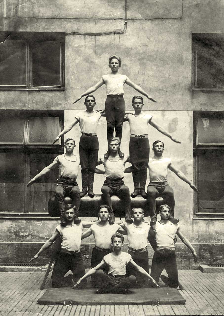 Львівські гімназисти-спортовці. Нагорі піраміди (вежі) – Роман Шухевич, внизу сидить Богдан Кордюк, в другому ряді перший зліва – Богдан Підгайний. Львів, вул. Руська, 20, у дворику біля рухівні “Сокола-Батька”. 18 жовтня 1922 р. З приватного архіву родини Богдана Підгайного.