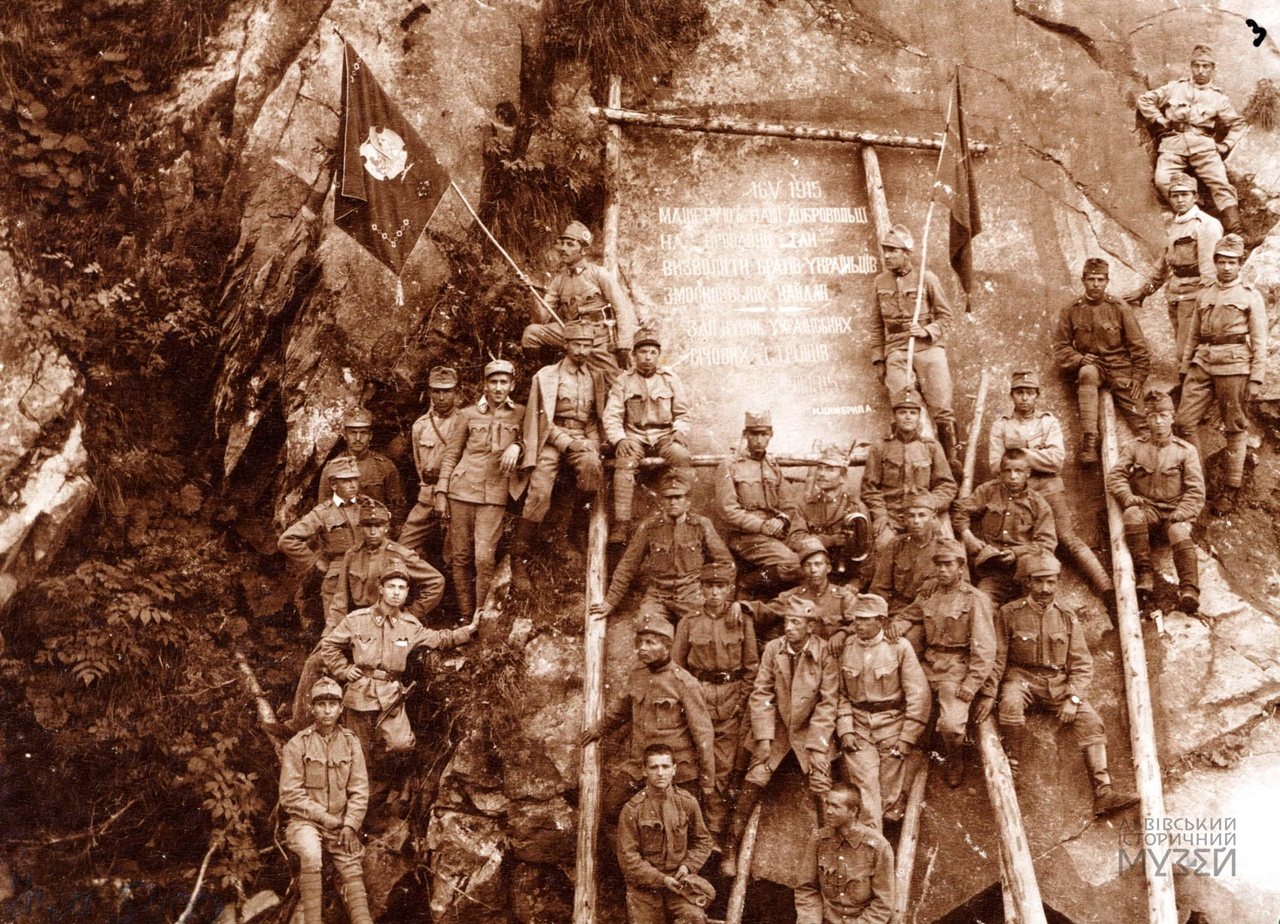 Група українських січових стрільців на схилі скали при дорозі до Камінки біля пам'ятної таблиці з написом: «16V1915 Машерують наші добровольці на кровавий тан — визволяти братів-українців з московських кайдан. Зап. Курінь українських січових стрільців…». Фондова колекція ЛІМ