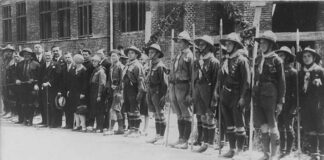 Дрогобицькі пластуни під час посвячення гімназії «Рідної школи», 1928 р. На церемонії присутні опікун Пласту в Дрогобичі о. Степан Венгринович, директор гімназії Володимир Кузьмович, сктм. Михайло Іваненко, кошовий Дрогобицького коша Петро Веприк, гості зі Львова Верховний Отаман Северин Левицький, ст. пл. Марія Охримович, ст. пл. Тарас Дурбак. Світлина опублікована: Сова А. Печатки 18 пластового куреня імени Івана Франка у Дрогобичі, 1920-ті рр. // Пластовий шлях. Журнал пластової думки та інформації. – Львів, 2023. – Чис. 3 (211). – С. 40–41.